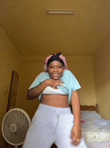 a girl is dancing in a bedroom with a fan