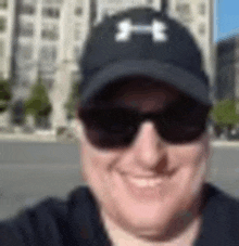 a man wearing a hat and sunglasses is smiling for the camera .