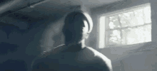 a man is standing in a dark room with a window .
