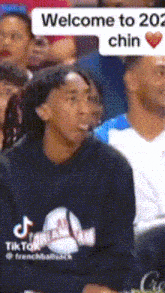a man sitting in a crowd with a welcome to 202 chin speech bubble above him