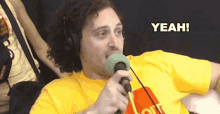 a man wearing headphones and a yellow shirt is holding a microphone and the word yeah is above him