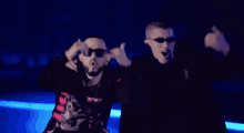 a man wearing sunglasses is standing next to another man wearing sunglasses