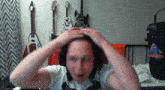 a man with a surprised look on his face is sitting in front of three guitars