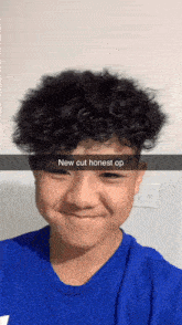 a young boy with curly hair is wearing a blue shirt and has a snapchat message on his face .