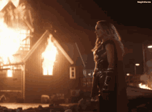 a woman in a cape stands in front of a burning building with the words magicwanda on the bottom
