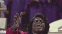 a man in a red robe is singing into a microphone