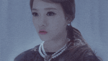 a woman wearing pearls and earrings looks down