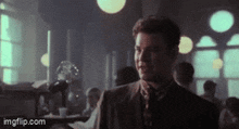 a man in a suit and tie is standing in a crowded room with imgflip.com at the bottom of the screen