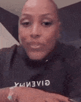 a close up of a woman 's face with a shaved head wearing a black sweater .
