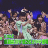 a girl in a green dress stands in front of a crowd with a sign that says " 2 "