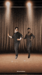 two men are dancing on a stage with the name ahmad kabbani on the bottom right