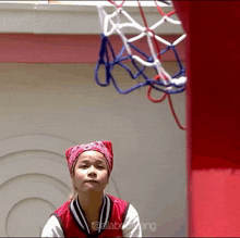 a girl wearing a red bandana stands in front of a basketball hoop