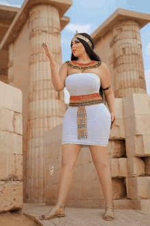 a woman in a white dress is standing in front of columns