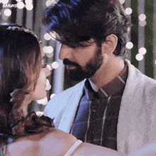 a man and a woman are kissing each other in front of lights .