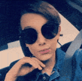 a young girl wearing sunglasses and a denim jacket