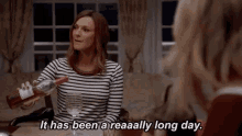 a woman is pouring wine into a glass and saying it has been a reaaally long day .