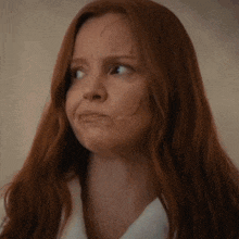 a close up of a woman with long red hair making a face .