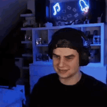 a man wearing headphones and a hat is smiling in front of a neon sign that says ' s ' on it
