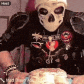 a man wearing a skull mask is holding a piece of cake with the name mad dawg asl on the bottom right