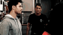 two men standing next to each other with one wearing a black shirt that says 13 on it