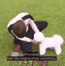 a man is kneeling down next to a small white dog and talking to it .