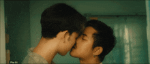 a couple of men kissing in front of a screen that says play ( n)