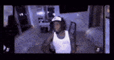 a man in a white tank top is sitting in a chair in a room .