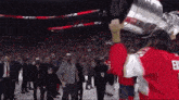 a hockey player holds up a trophy while wearing a jersey with the letter e on the back