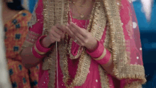 a woman in a pink and gold dress is holding a string in her hands .