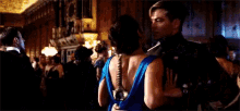 a woman in a blue dress is dancing in a crowded room with other people .