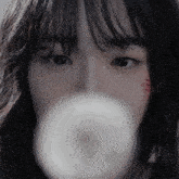 a close up of a woman 's face with a white object in her mouth