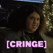 a woman with curly hair is smiling in front of a sign that says cringe