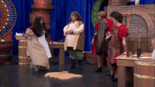 a woman in a dress is dancing on a stage with other people