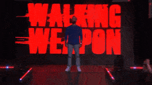 a man is standing in front of a screen that says walking weapon