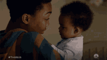 a person holding a baby with a nbc logo on the bottom right