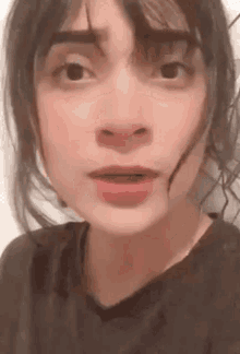a close up of a woman 's face with her mouth open and a black shirt on .