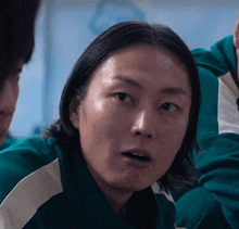a close up of a woman 's face in a green jacket