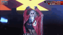 a woman in a red jacket and sunglasses is dancing on a stage in front of a sign that says stardom