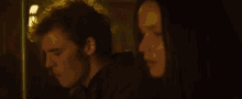 a man and a woman are standing next to each other in a dark room looking at each other .