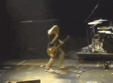 a person is playing a guitar on a stage in a dark room