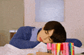 a young man is sleeping on a pile of papers next to a stack of markers .