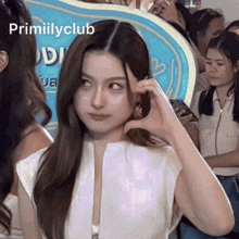a woman making a heart shape with her hand in front of a sign that says ' primiilyclub '