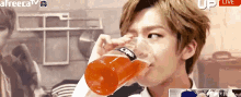 a young man is drinking a bottle of orange juice from a glass ..