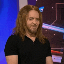 a man with long hair and a beard wearing a black shirt