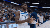 a basketball player wearing a wolves jersey applauds during a game