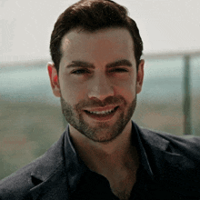a man with a beard is smiling and wearing a suit jacket