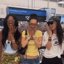 three women are posing for a picture in front of an everyday low price sign