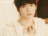 a young man wearing a necklace and a white shirt with the words powercircles on the bottom right