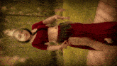 a woman in a red dress is standing on a wooden deck with trees in the background