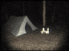 a tent is lit up in the dark with a few candles